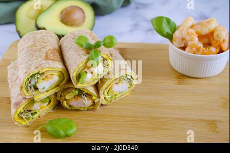 Käsetortilla mit Avocado-Garnelen und Gemüse auf Holzschneidebrett. Tortilla mit Gemüse, Garnelen und Luzerne gekeimt. Tortilla aus Stockfoto