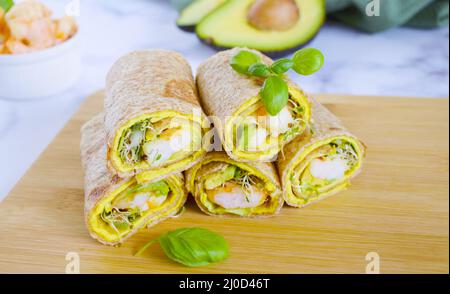 Käsetortilla mit Ei-Avocado-Garnelen und Gemüse auf Holzschneidebrett. Tortilla mit Gemüse, Garnelen und Luzerne gekeimt. Tortilla f Stockfoto
