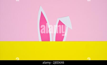 Hasenohren auf pastellrosa und gelbem Hintergrund. Flat Lay minimales kreatives Konzept Stockfoto