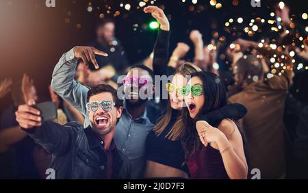 Jetzt ist das, wie Sie feiern. Eine kurze Aufnahme einer vielfältigen Gruppe junger Freunde, die bei einer Party in der Nacht ein Selfie zusammen machen. Stockfoto