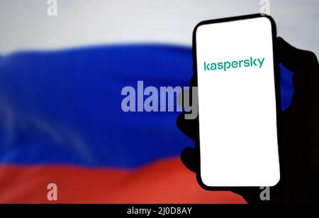 Rom, Italien, März 2022: Das Logo von Kaspersky Antivirus auf dem Bildschirm eines Handheld-Mobiltelefons mit verschwommener russischer Flagge im Hintergrund Stockfoto