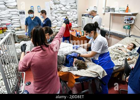 Saporischschschja, Ukraine. 18. März 2022. Mitarbeiter kümmern sich um ein Kind, während die Fenster im regionalen Kinderkrankenhaus Zaporizhzhia mit Sandsäcken versiegelt werden, wo Kinder, die während des Beschusses durch russische Truppen schwere Verletzungen erlitten haben, behandelt werden, Zaporizhzhia, im Südosten der Ukraine. 18. März 2022. Foto von Dmytro Smolyenko/Ukrinfrom/ABACAPRESS. Quelle: Abaca Press/Alamy Live News Stockfoto