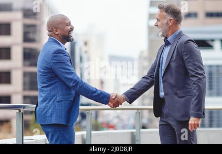 Ihr könnt die Bank auf mich wetten. Kurzer Schuss von zwei Geschäftsleuten, die draußen die Hände schüttelten. Stockfoto