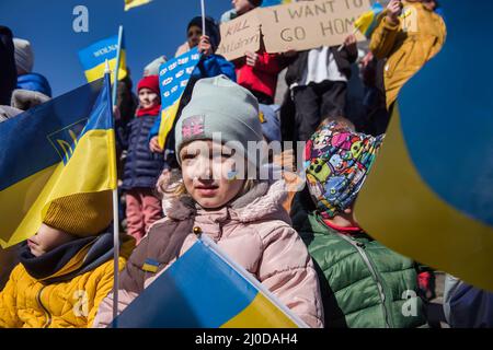 Warschau, Polen. 18. März 2022. Ukrainische Kinder halten Plakate und schwenken ukrainische Flaggen während des Protestes. Der "Marsch der ukrainischen Mütter" fand in Warschau statt, der auch ein Protest gegen den Krieg und die Tötung ukrainischer Kinder war. Die Parolen des marsches waren: "Welt, helft unseren Kindern", "Stoppt den Krieg", "rettet Kinder der Ukraine" und "schließt den Himmel". An dem Protest nahmen vor allem ukrainische Mütter und ihre Kinder Teil, die vor dem Krieg in Polen Zuflucht fanden. (Foto von Attila Husejnow/SOPA Images/Sipa USA) Quelle: SIPA USA/Alamy Live News Stockfoto