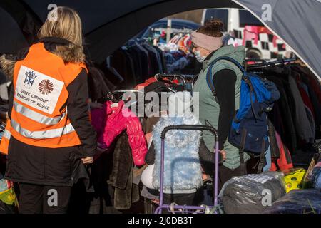 Vysne Nemecke, Slowakei. 18. März 2022. In Vysne Nemecke, an der slowakischen Grenze zur Ukraine, nimmt eine Frau (r), die aus der Ukraine geflohen ist, eine dicke Jacke mit gespendeter Kleidung für ihre junge Tochter heraus. Quelle: Christoph Reichwein/dpa/Alamy Live News Stockfoto