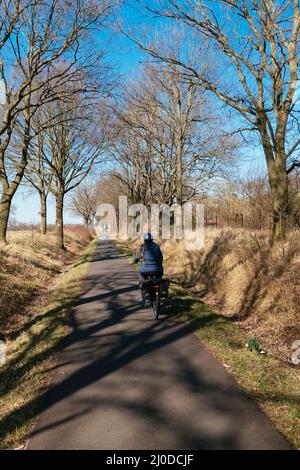 Frau auf einem E-Bike auf der Weser-Radroute bei Petershagen. Stockfoto