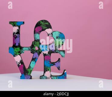 Holzwort Liebe auf farbigem Hintergrund beleuchtet. Muttertag, Valentinstag´s-Konzept. Liebeskonzept Stockfoto
