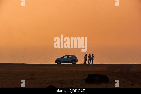 Sindhudurg, INDIEN - 23. Dezember 2021 : Silhouette von Männern und einem Auto mit Meerblick vom Tischpunkt am Fort Devgad Stockfoto