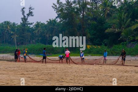 Malvan, Indien - 20. Dezember 2021 : Indische Fischer mit Fischernetz an der Küste. Stockfoto