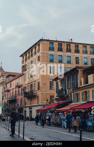 Nizza, Frankreich - 10. März 2022: Menschen, die an Souvenirläden auf der Cours Saleya vorbeilaufen, der größten Fußgängerzone in Vieux Nice (Altstadt), für die sie am besten bekannt ist Stockfoto