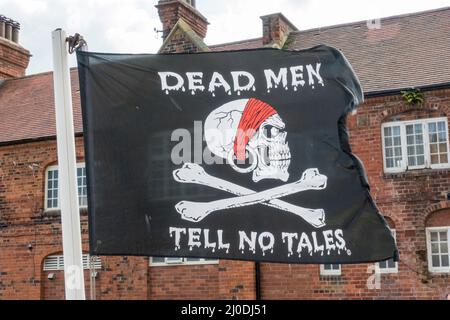 „Dead Men Tell No Tales“-Piratenflagge (Totenkopf und Kreuzknochen), die in Scarborough, einem Badeort an der Nordsee in North Yorkshire, Großbritannien, fliegt Stockfoto