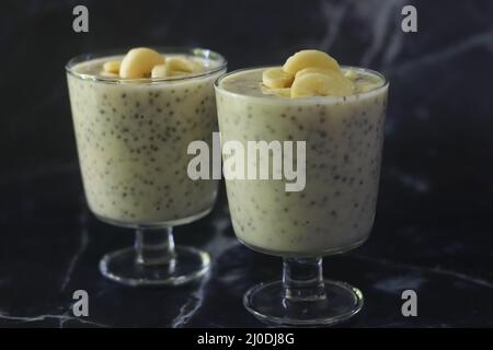 Melkenshake aus Kochbananen und eingeweichten Chiasamen. Aufgenommen auf schwarzem Granit-Hintergrund Stockfoto