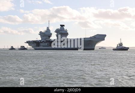 Schlepper begleiten den Flugzeugträger der Royal Navy, HMS PRINCE OF WALES, während er sich dem Marinestützpunkt nähert Stockfoto