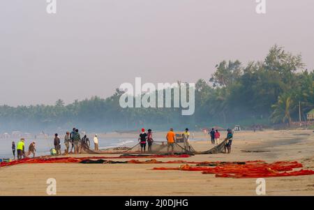 Malvan, Indien - 20. Dezember 2021 : Indische Fischer mit Fischernetz an der Küste. Stockfoto