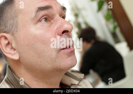 Der überraschte reife Mann in einem Restaurant Stockfoto