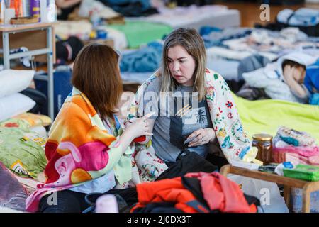 UZHHOROD, UKRAINE - 18. MÄRZ 2022 - in Decken gewickelte Frauen werden in einer Turnhalle einer akademischen Institution abgebildet, in der fast 300 interne Disps untergebracht sind Stockfoto