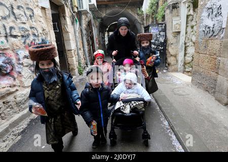 Jerusalem. 18. März 2022. Während des jüdischen Feiertages von Purim in Jerusalem am 18. März 2022 werden verkleidete jüdische Kinder auf einer Straße gesehen. Purim ist ein jüdischer Feiertag, der an die Befreiung des jüdischen Volkes von Hamans Verschwörung während der Herrschaft des alten persischen Reiches gemäß dem biblischen Buch Esther erinnert. Quelle: Gil Cohen Magen/Xinhua/Alamy Live News Stockfoto