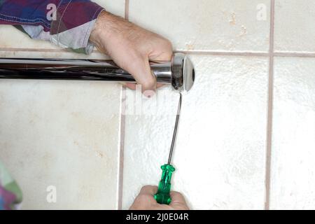 Arbeiter montiert einen Handtuchhalter an einer Wand Stockfoto