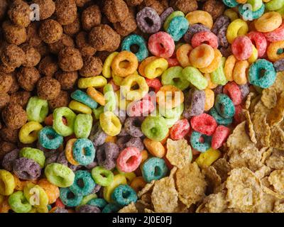 Verschiedene Vollkornfrühstücke - Schokoladenkugeln, bunte Obstringe, knusprige Flocken. Schnelles Frühstück, Kinderkost, Diätkost. Supermarkt. Erw Stockfoto