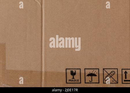Abgenutzte Kartonstruktur mit transparentem Klebeband und Sicherheitssymbolen Stockfoto