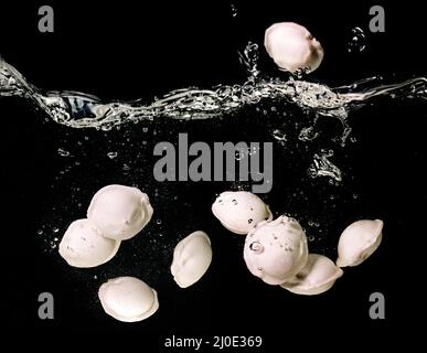 Knödel (Ravioli) unter Wasser in kochendem Wasser unter Wasser in einer Pfanne auf dunklem Hintergrund. Essen, italienische, chinesische Küche Stockfoto