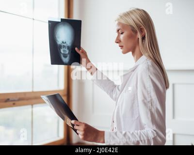 Ärztin hält Röntgenstrahlen und schaut sie an. Stockfoto