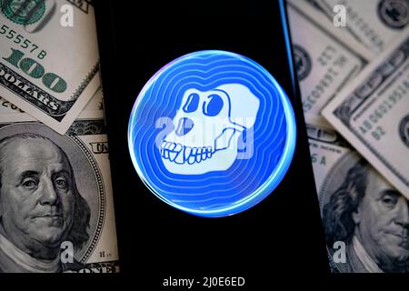 ApeCoin Krypto-Token-Logo auf dem Smartphone, das auf Dollar platziert ist gesehen. Neue Kryptowährung vom NFT Bored Ape Yacht Club. Stafford, Großbritannien Stockfoto