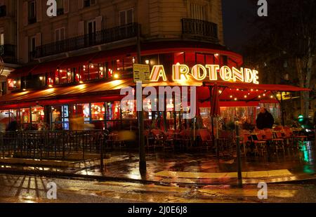 Das berühmte Café La Rotonde bei regnerischer Nacht. Es liegt am Montparnasse Boulevard, Paris, Frankreich. Stockfoto