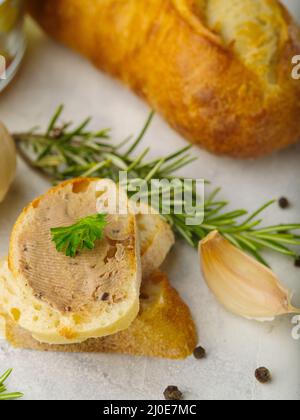 Nahaufnahme. CANape mit Foie Gras, Knoblauch und Rosmarin-Zweige. Im Hintergrund ein Baguette. Isoliert auf weißem Hintergrund. Restaurant, Hotel, Bankett Stockfoto