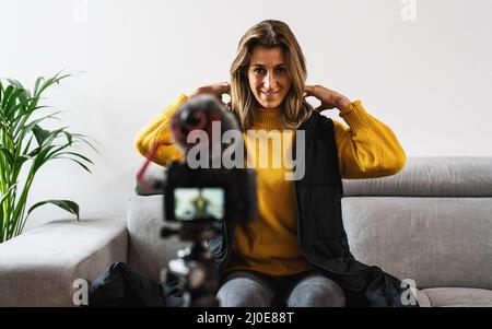 Weibliche Influencer, die Inhalte für Online-Vlog oder Produktpräsentationen aufzeichnet, Frau, die die Kamera anschaut und über Videoaufnahmen mit Technologie spricht Stockfoto
