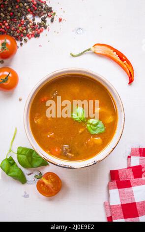 Tomatensuppe mit Fleisch in einer weißen Schüssel auf weißem Holz- Hintergrund Stockfoto