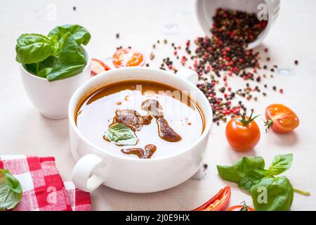 Tomatensuppe mit Fleisch in einer weißen Schüssel auf weißem Holz- Hintergrund Stockfoto