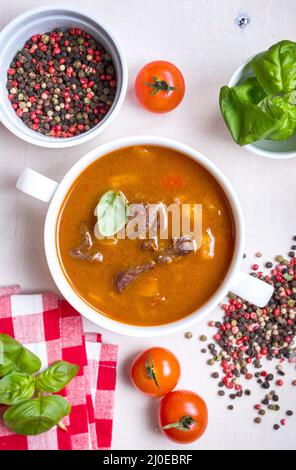 Tomatensuppe mit Fleisch in einer weißen Schüssel auf weißem Holz- Hintergrund Stockfoto