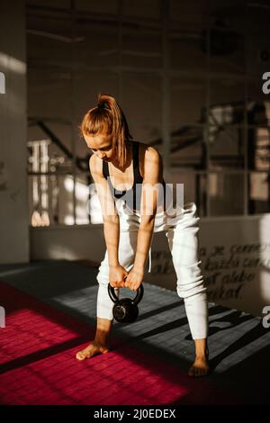 Junge Schönheit stark fit Mädchen hält schwere Kettlebell und tun Swing Hardcore Crossfit Training im Fitnessstudio. Stockfoto