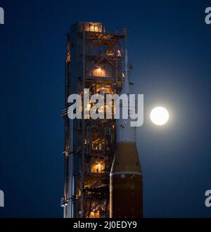 Cape Canaveral, Florida, USA. 17. März 2022. Der Mond steigt hinter der NASA-Rakete Space Launch System (SLS) mit der Orion-Sonde auf einem mobilen Trägerrakete auf, während er zum ersten Mal im Kennedy Space Center der NASA in Florida zum Launch Complex 39B ausrollt. Im Vorfeld des Artemis I-Flugtests der NASA werden die vollständig gestapelte und integrierte SLS-Rakete und die Orion-Raumsonde im Launch Complex 39B einer Nassprobe unterzogen, um die Systeme zu verifizieren und Countdown-Verfahren für den ersten Start zu üben. Quelle: NASA/Aubrey Gemignani/ZUMA Press Wire Service/ZUMAPRESS.com/Alamy Live News Stockfoto