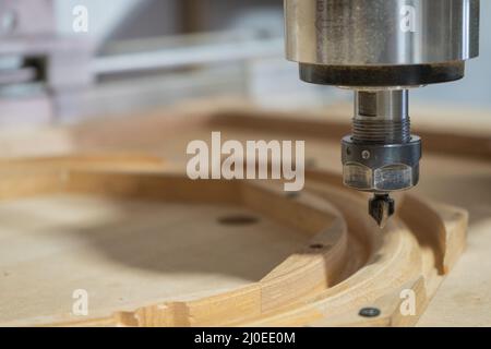 cnc-Fräser bei der Arbeit in der Werkstatt, die ein hölzernes Lenkrad für einen Oldtimer herstellt Stockfoto