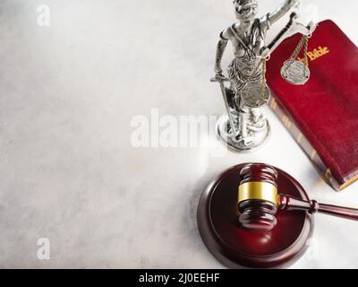 Richtergavel, Skulptur der Göttin der Gerechtigkeit - Themis und die Bibel auf weißem Hintergrund. Low-Angle-Ansicht. Gerechtigkeit, Rechtssymbole, Verfassung Stockfoto