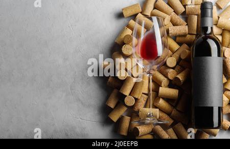 Viele Weinkorken und ein Glas Rotwein. Isoliert auf grauem Hintergrund. Auf dem Foto befinden sich keine Personen. Es ist freier Speicherplatz zum Einfügen vorhanden. Restaurant Stockfoto