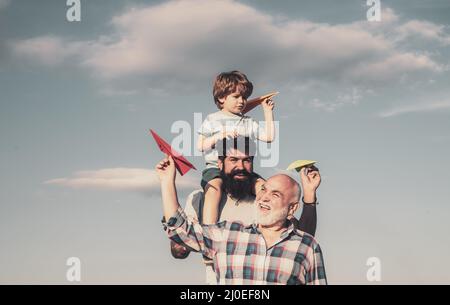 Vatertag - Großvater, Vater und Sohn umarmen sich und haben Spaß zusammen. Das Flugzeug ist flugbereit. Porträt eines glücklichen Vaters, der dem Sohn Huckepack gibt Stockfoto