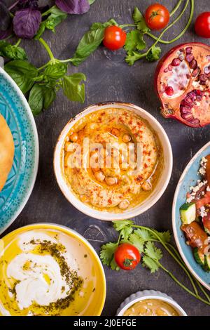 Tisch serviert mit dem Nahen Osten vegetarische Gerichte. Hummus, Tahini, pitta, couscous Salat und Buttermilch Dip mit Olivenöl Stockfoto