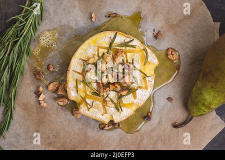 Köstliche Gebackene Camembert mit Honig, Nüssen, Kräutern und Birnen Stockfoto
