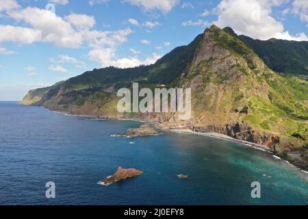 Aus der Vogelperspektive auf Madeiras Nordküstenklippen und das tiefblaue Atlantikwasser in der Nähe von Boaventura mit zerklüfteten vulkanischen Formationen und unberührter Küste. Stockfoto