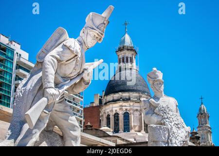 Skulpturen mit Soldaten und Kirchen im Hintergrund. Rosario, Santa Fe, Argentinien. Stockfoto