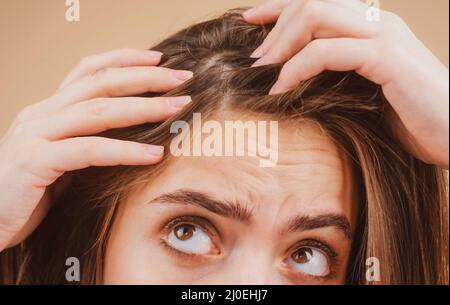 Nahaufnahme einer Frau, die ihre Haare und ihre Haare, Haarausfall am Haaransatz oder trockenes Kopfhautproblem untersucht. Stockfoto