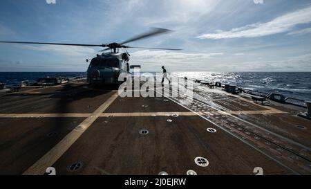 PHILIPPINISCHE SEE (17. März 2022) der Mate 2. Class Isaac Firlit von Aviation Electrician aus Swanswen, Massachusetts, überquert das Flugdeck, um vor dem Start eines Hubschraubers MH-60R Sea Hawk, der den „Raptors“ des Helicopter Maritime Strike Squadron (HSM 71) zugewiesen wurde, eine abschließende Inspektion zu absolvieren. Vom Flugdeck des Arleigh Burke-Klasse Lenkraketen-Zerstörers USS Spruance (DDG 111). Die Abraham Lincoln Strike Group befindet sich im geplanten Einsatzbereich der US-Flotte für 7., um die Interoperabilität durch Allianzen und Partnerschaften zu verbessern und gleichzeitig als einsatzbereite Truppe zur Unterstützung eines f Stockfoto