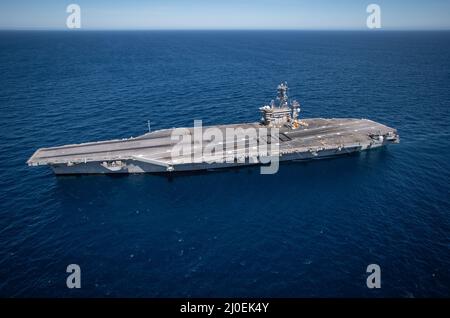 220312-N-NH257-1050 PAZIFISCHER OZEAN (MÄRZ 12, 2022) Seeleute an Bord der USS Nimitz (CVN 68) versammeln sich auf dem Flugdeck und bilden eine menschliche '100', um des hundertjährigen Jubiläums des Flugzeugträgers zu gedenken. Am 20. März 1922 wurde die ehemalige USS Jupiter (Collier #3) als USS Langley (CV 1), der erste Flugzeugträger der US Navy, wieder in Betrieb gesetzt. Hundert Jahre später bilden Flugzeugträger der Nimitz- und Ford-Klasse den Grundstein für die Fähigkeit der Marine, die Meereskontrolle aufrechtzuerhalten und Strom an Land zu projizieren. Nimitz ist der erste seiner Klasse und der älteste beauftragte Flugzeugträger im Wasser, der ein Vermächtnis von trägt Stockfoto