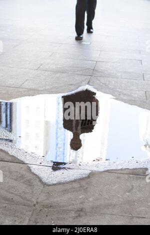 Kaukasischer Geschäftsmann verlässt das Büro über eine Pfütze auf seinem Weg nach Hause Themen des Hindernisses p Stockfoto