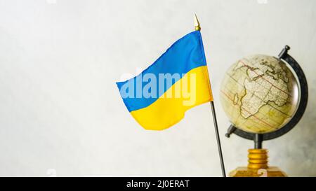 Globus und Nationalflagge der Ukraine. Die Ukraine in der Geopolitik, Russlands Invasion des Territoriums eines unabhängigen Staates, Krieg, Tötungen von Zivilisten Stockfoto