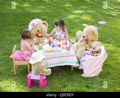 Erhöhte Ansicht von zwei jungen Mädchen spielen Teddybären Picknick in ihrem Garten Themen imaginati Stockfoto