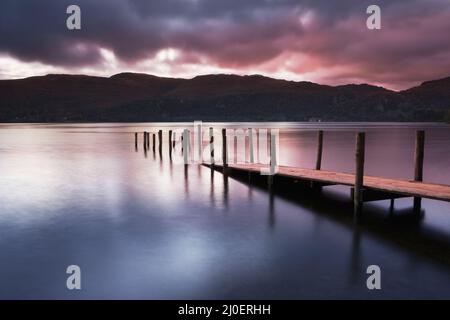 Ein Blick über den Derwent Water Lake bei Sonnenaufgang, mit Jetty im Vordergrund. Lake District Cumbria England Stockfoto